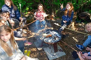 Kinder beim Lagerfeuer im Wald, Natur erleben, Achtsamkeit, Gemeinschaft.