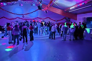 Menschen tanzen bei einer festlichen Veranstaltung in Zingst, beleuchtet mit bunten Lichtern.
